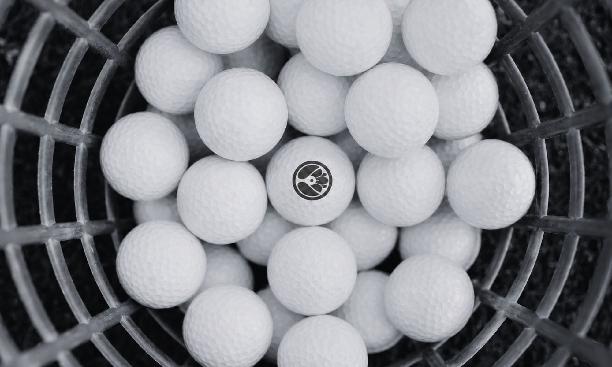 White  golf balls with konohana logo in a black metal basket